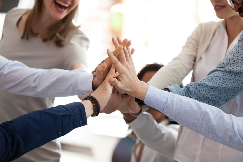 Excited happy multiracial team giving high five, celebrating good results, congratulating with success at briefing, group of employees rejoicing at achieved goal, good teamwork, collaboration, close up